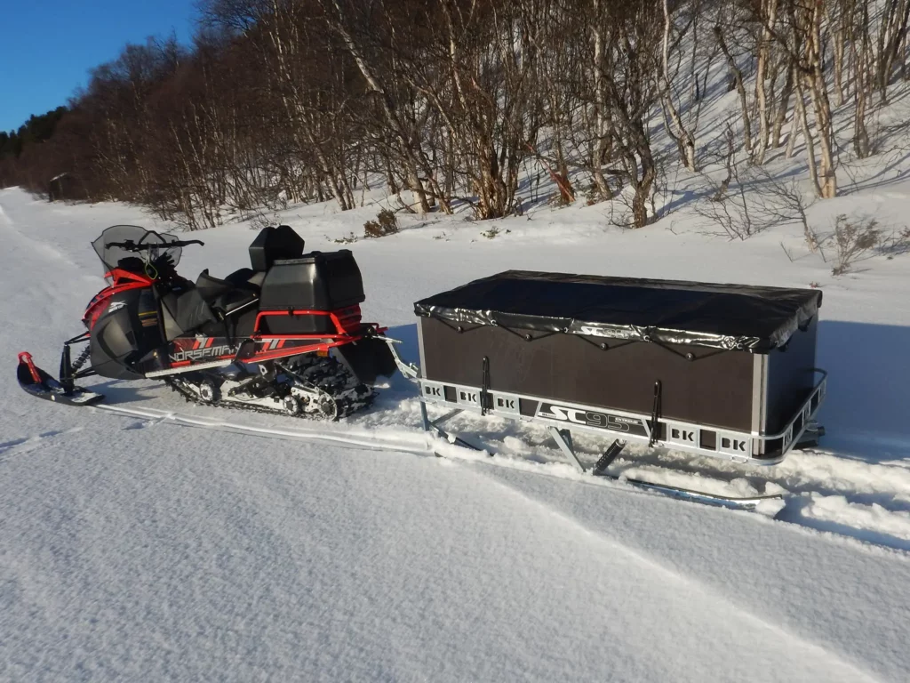 Snøscooter og kjelke i snø.