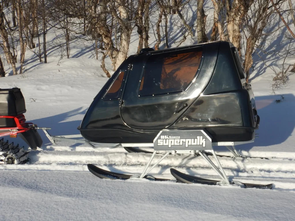 Superpulk som trekkes av snøscooter i snøen.